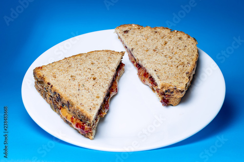 Peanut butter and jelly sandwich on white glass plate