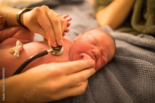 Midwife checking newborn baby at home photo