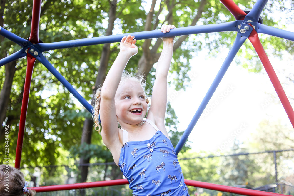Happy cute girl climbing jungle gym against trees at playground Happy cute girl climbing jungle gym against trees at playground