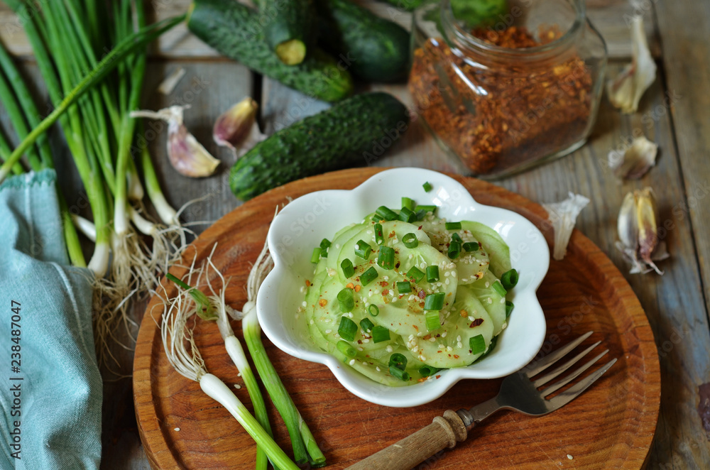 Cucumber salad with chives in a white bowl on a wooden board