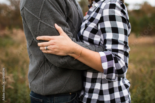 Midsection of romantic couple embracing while standing in forest photo