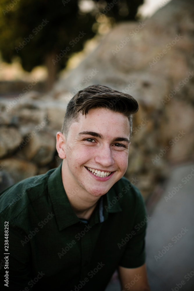 Close-up portrait of happy handsome man sitting against rock formations at park Close-up portrait of happy handsome man sitting against rock formations at park