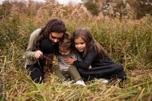 Cute sisters sitting on grassy field in forest photo