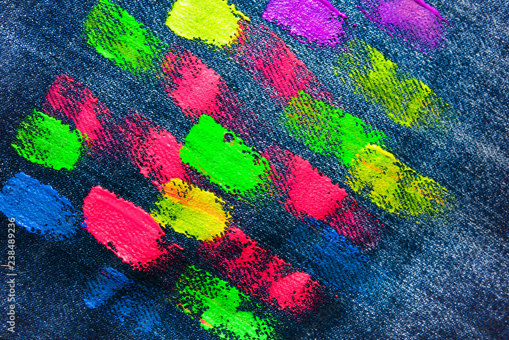 The texture of denim with strokes of fluorescent gouache color paint. Abstract background jeans