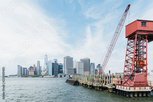 Modern buildings by Governors Island against cloudy sky in city photo