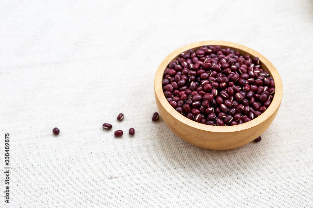 Small raw red bean in round wooden bowl on canvas background, organic bean, vegetarian food Small raw red bean in round wooden bowl on canvas background, organic bean, vegetarian food