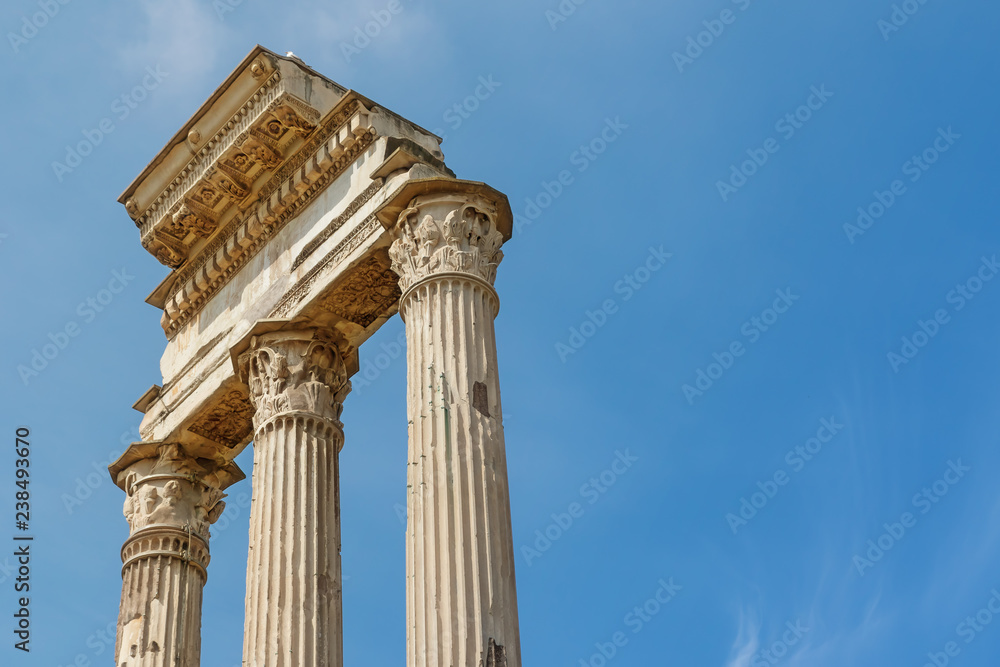 Ruins of the iconic three columns in Forum Romanum with free place for your text. Rome. Italy. Blue sky on the background. Horizontally.