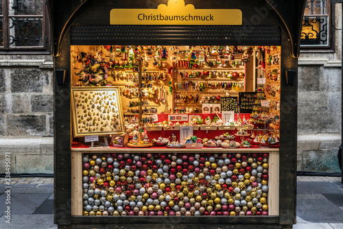 Vienna, Austria - December 21, 2017. Winter seasonal stand selling Christmas glass ornaments and souvenirs at traditional Xmas market. Illuminated fair kiosk with decor near St. Stephen's Cathedral.