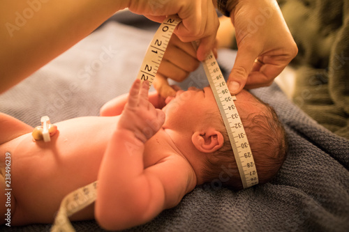 Close up of midwife measuring newborn baby head photo