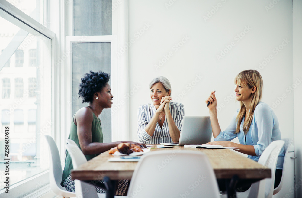 Happy businesswomen discussing at conference table in creative office Happy businesswomen discussing at conference table in creative office