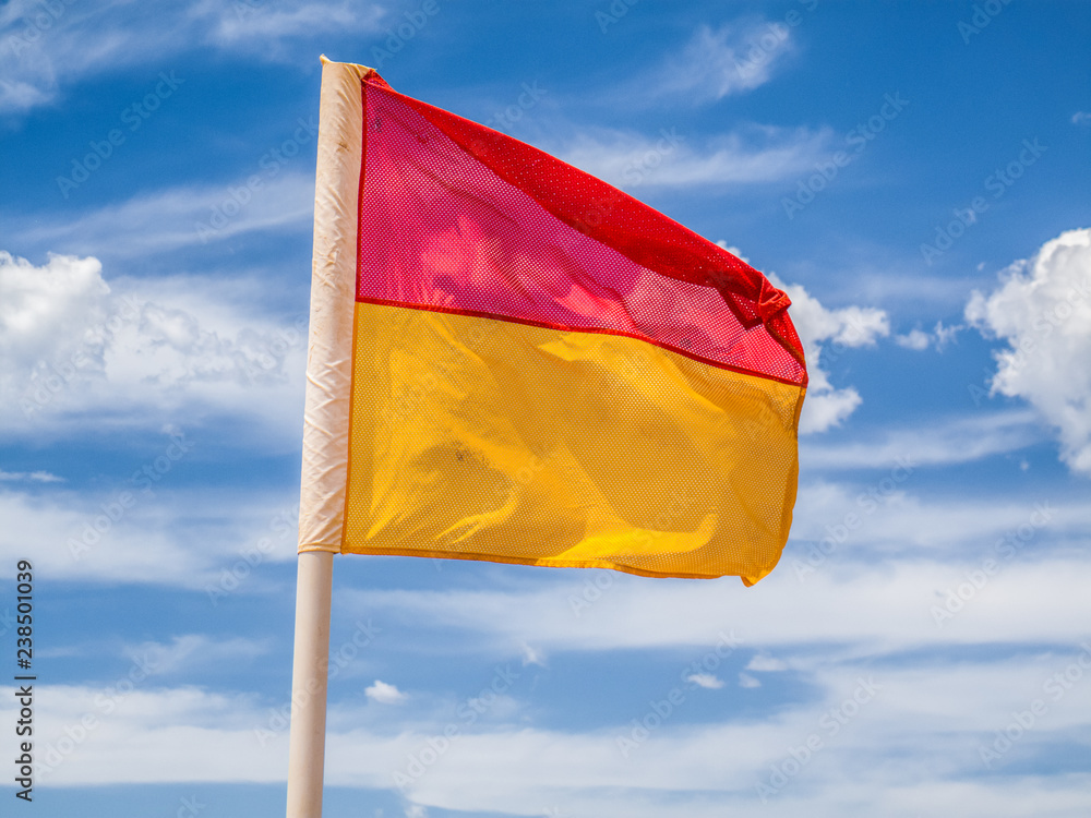 Red and yellow beach safety flag against a cloudy sky Red and yellow beach safety flag against a cloudy sky