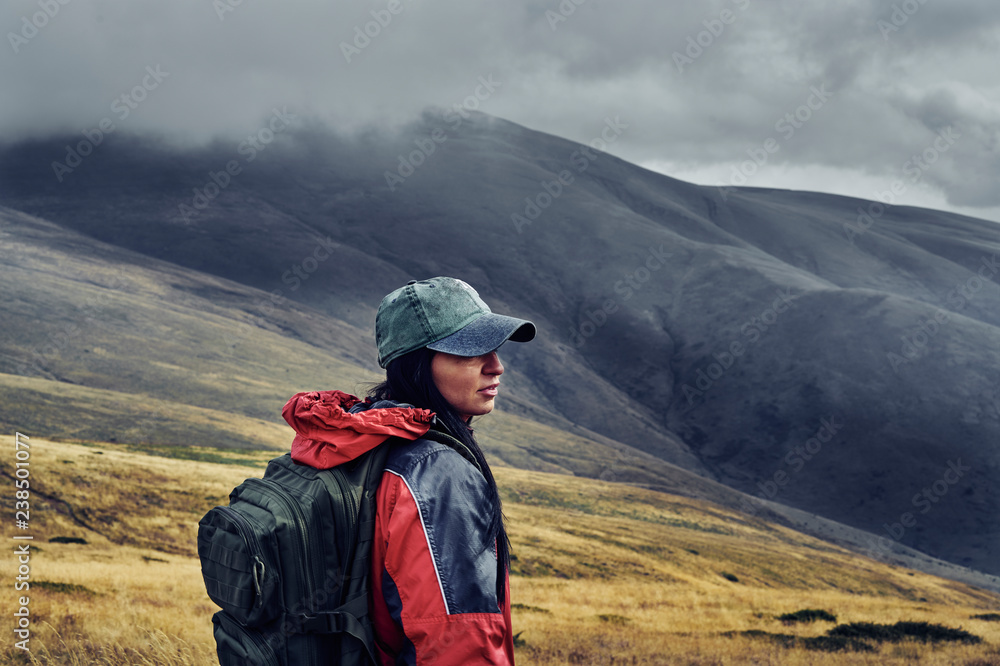 Side view of female hiker with backpack standing on Balkan Mountains against cloudy sky Side view of female hiker with backpack standing on Balkan Mountains against cloudy sky