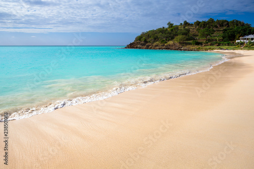 Tropical beach at Antigua island in Caribbean with white sand, turquoise ocean water and blue sky