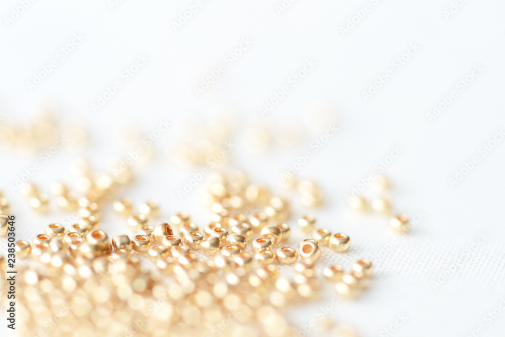 Golden seed beads scattered on textile background close up Golden seed beads scattered on textile background close up