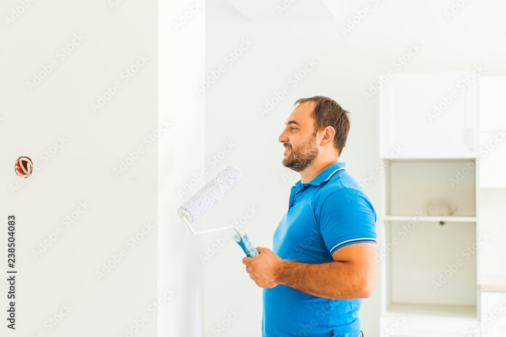 Young smiling painter looking at whitewashed wall