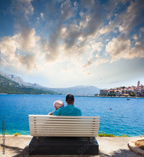 Young couple is sitting on the bench in front of sea