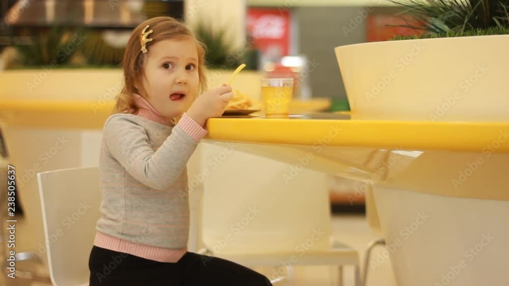 Child girl eating fast food french fries in a cafe. Child girl eating fast food french fries in a cafe.