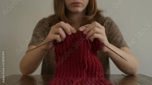 Knitting a red scarf at a wooden table