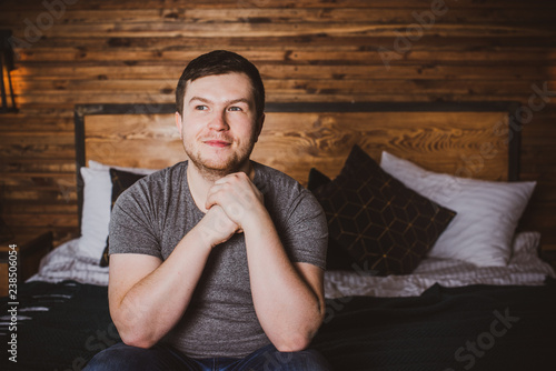 Fotografie Handsome man is looking away sitting at bedroom in home