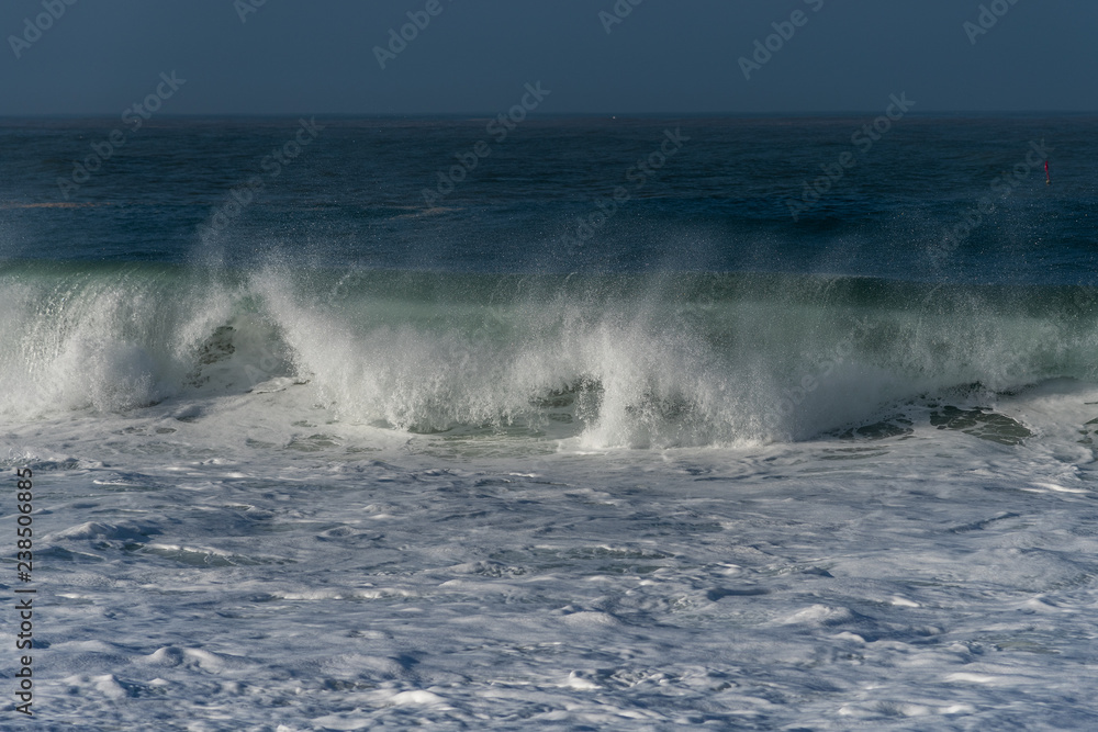 Foamy Atlantic ocean wave on Nazare city beach, Portugal.