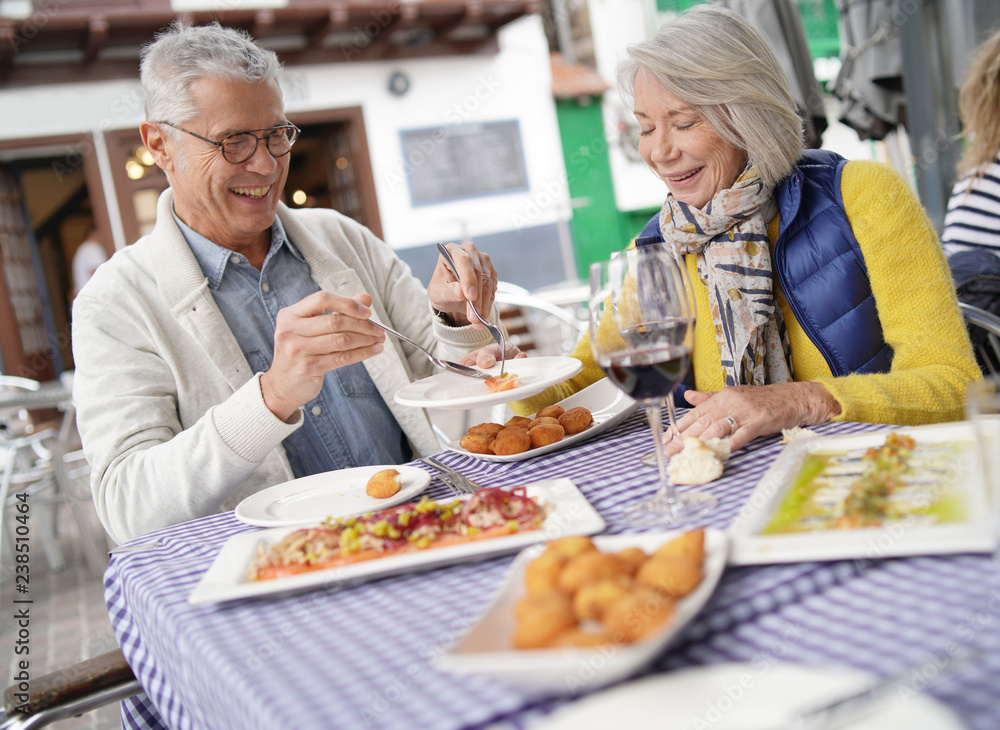 Attractive senior couple eating tapas outdoors Attractive senior couple eating tapas outdoors