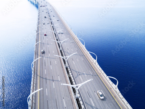Aerial view of highway in the ocean. Cars crossing bridge interchange overpass. Highway interchange with traffic. Aerial bird's eye highway. Expressway. Road junction. Car passing. Bridge with traffic