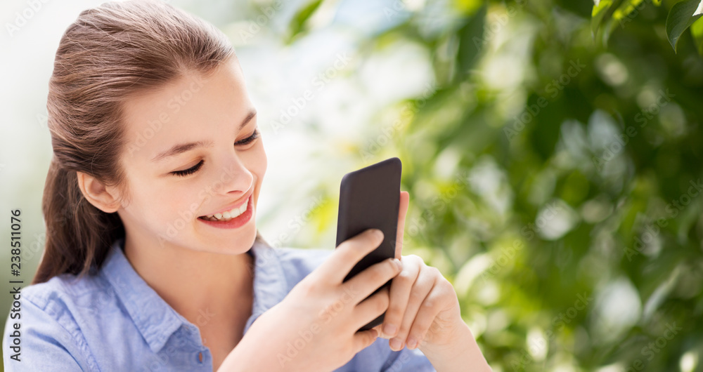 people, technology and communication concept - smiling girl messaging on smartphone over green natural background people, technology and communication concept - smiling girl messaging on smartphone over green natural background