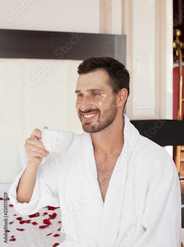 Bearded man in bed drinking morning espresso coffee in sunrise light