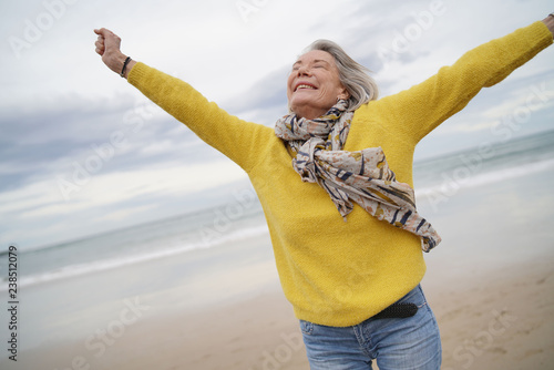  Carefree energetic senior woman playing around on beach in fall photo
