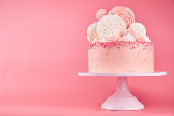 Birthday pink cake, decorated with meringue cookies on a pink background.