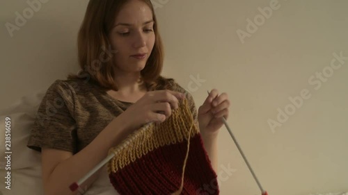 Woman knitting a scarf in bed