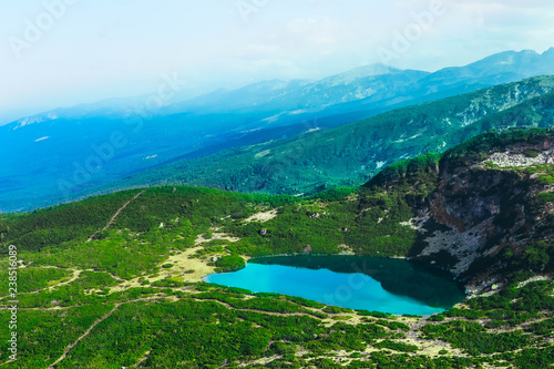 Fototapeta Naklejka Na Ścianę i Meble -  Alpine mountain lake, green meadows, hiking trail. Amazing valley landscape.