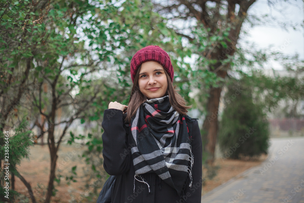 Portrait of a beautiful girl in a red hat and black coat that looks away and smiles. Portrait of a beautiful girl in a red hat and black coat that looks away and smiles.