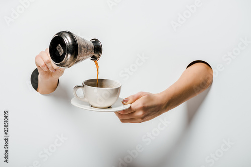 cropped image of woman pouring coffee from cezve into cup through holes on white