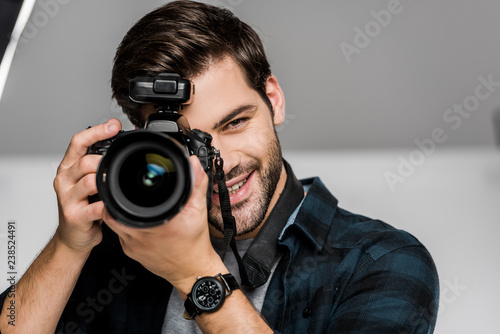 handsome happy young man photographing with camera in studio
