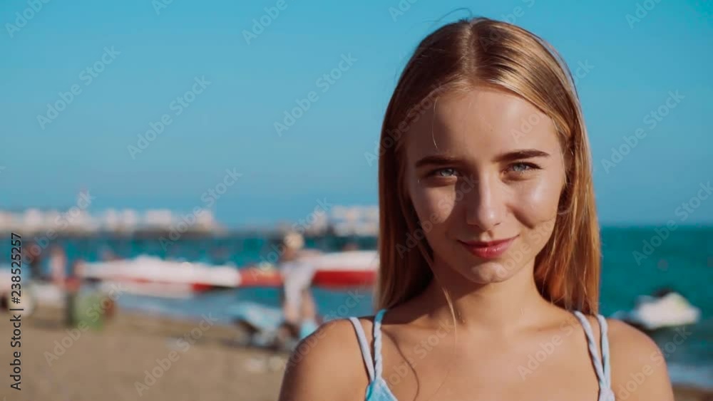 Portrait young blonde attractive woman look at camera smile happy near sea relax holiday paradise swimwear travel beautiful sunlight water enjoying beach adult beauty girl close up slow motion Portrait young blonde attractive woman look at camera smile happy near sea relax holiday paradise swimwear travel beautiful sunlight water enjoying beach adult beauty girl close up slow motion