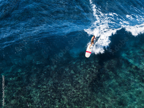 Aerial view of the surfer riding the perfect crystal clear wave of Oahu island, Hawaii