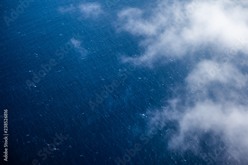 Aerial view of the sea surface with some clouds above it