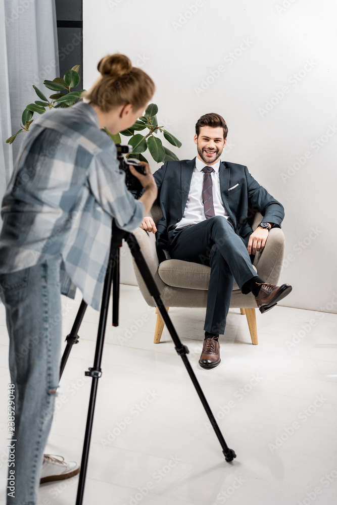 back view of young photographer taking pictures of handsome smiling businessman in office back view of young photographer taking pictures of handsome smiling businessman in office