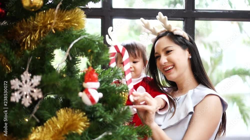 Mom and child daughter decorate the Christmas tree indoors. Closeup portrait of loving family, Merry Christmas and Happy Holidays! Mom and child daughter decorate the Christmas tree indoors. Closeup portrait of loving family, Merry Christmas and Happy Holidays!