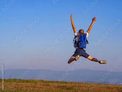 Backpacker jumping up on a hill and hands up and enjoying the view. Freedom and unity with nature. Tourist outdoors enjoying the scenery.