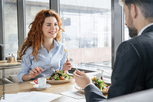 Businesspeople having business lunch at restaurant sitting eating salad drinking espresso talking cheerful photo