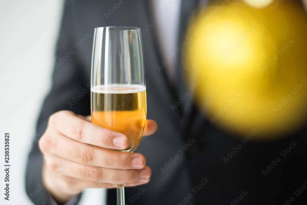 Closeup of man holding blurred Christmas ball and glass with champagne. Person celebrating Christmas. Christmas party concept. Isolated cropped front view on white background. Closeup of man holding blurred Christmas ball and glass with champagne. Person celebrating Christmas. Christmas party concept. Isolated cropped front view on white background.