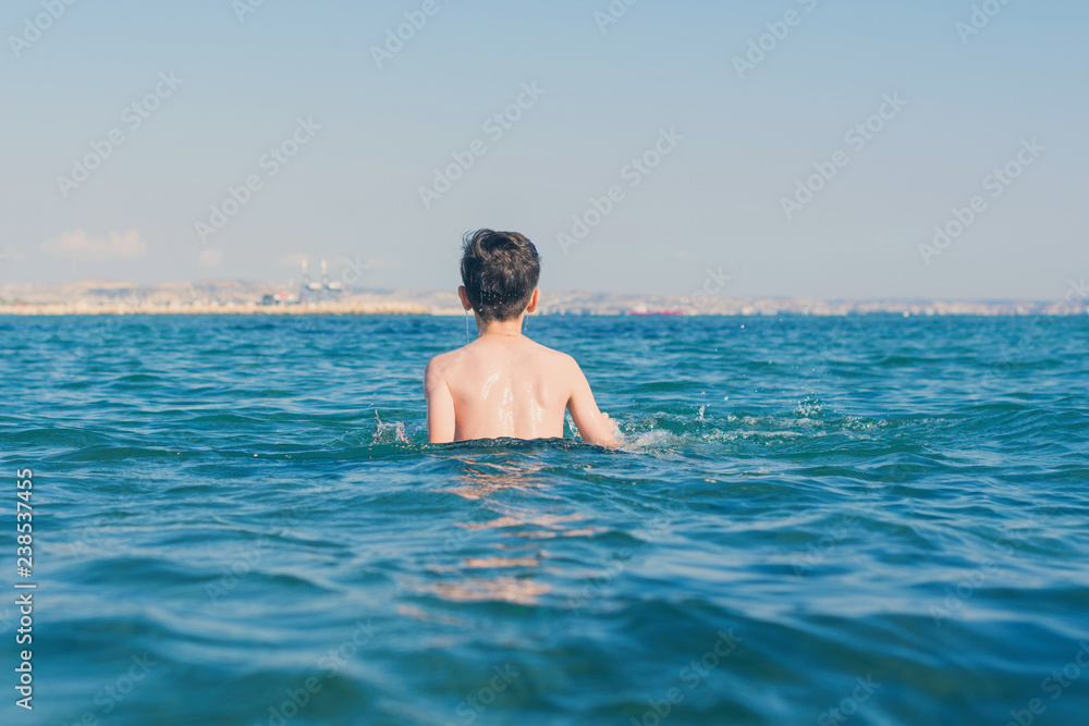 Happy and smiling teen boy swimming in the sea. Travel and summer concept