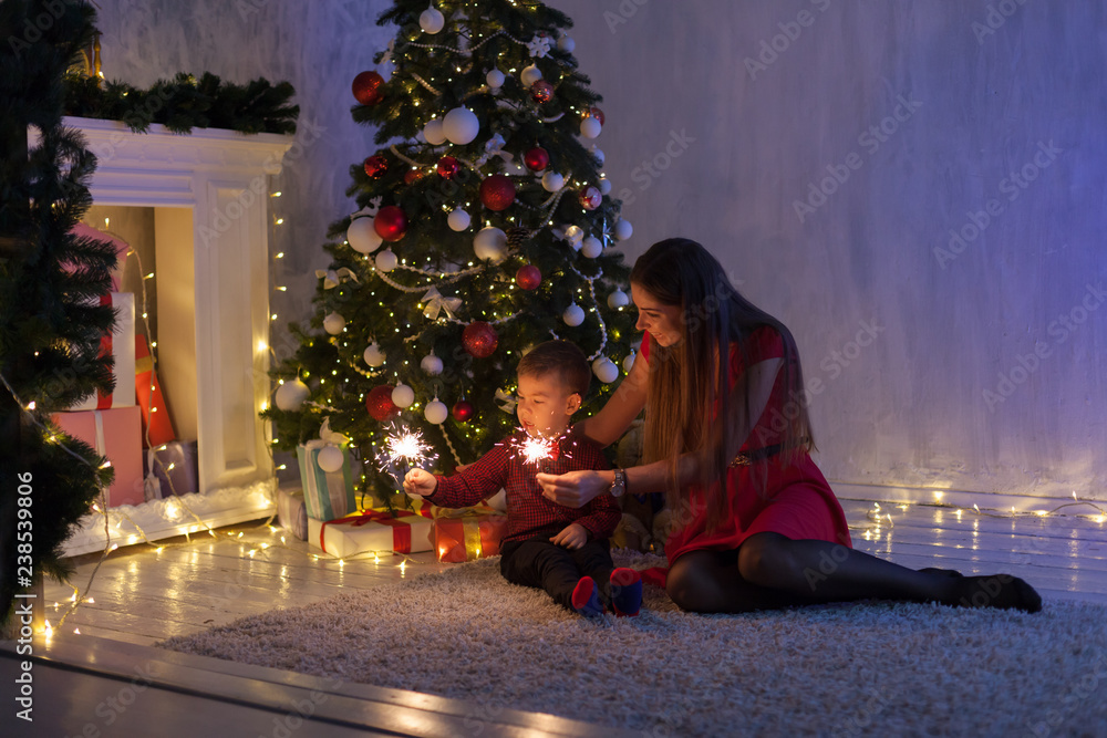 Obraz premium mother and young son sparklers gifts new year Christmas tree