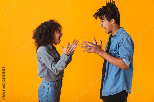 Young african couple standing isolated over yellow