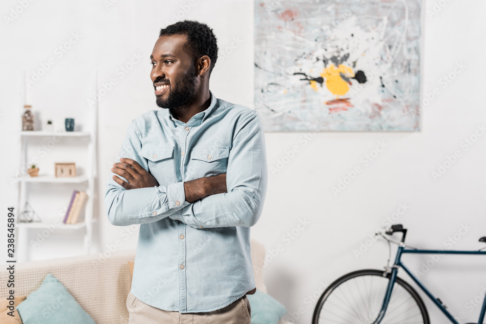 african american man standing with arms crossed in living room