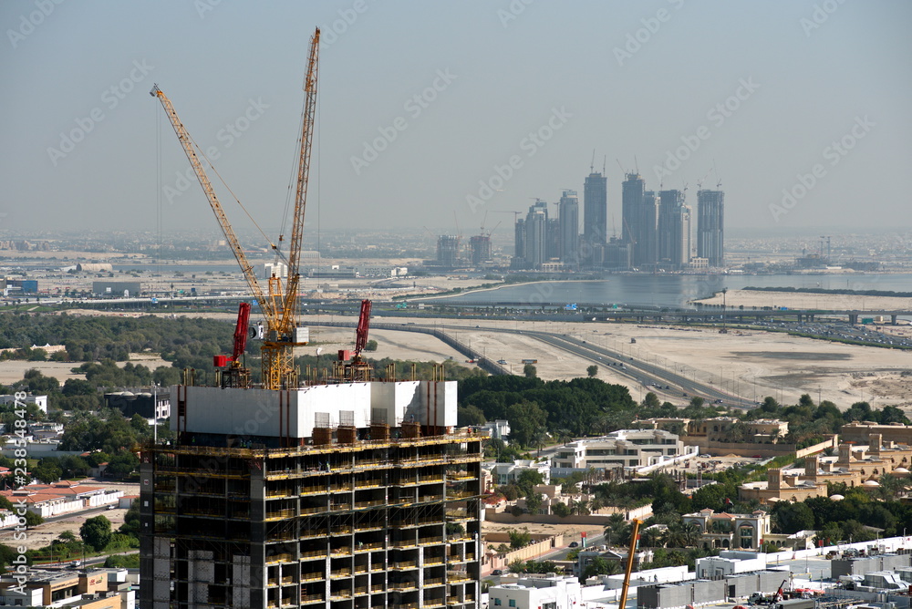 Fototapeta premium Aerial view of under construction building with cranes from downtown, visible whole Zabeel district, Dubai Creek harbor, Dubai Canal to Business Bay and Al Khail road