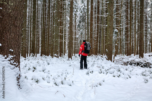 hiker male walking with backpack in snowy winter forest