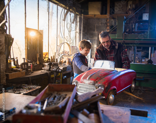 Принти на полотні Father and his young son in a DIY workshop to repair a pedal car